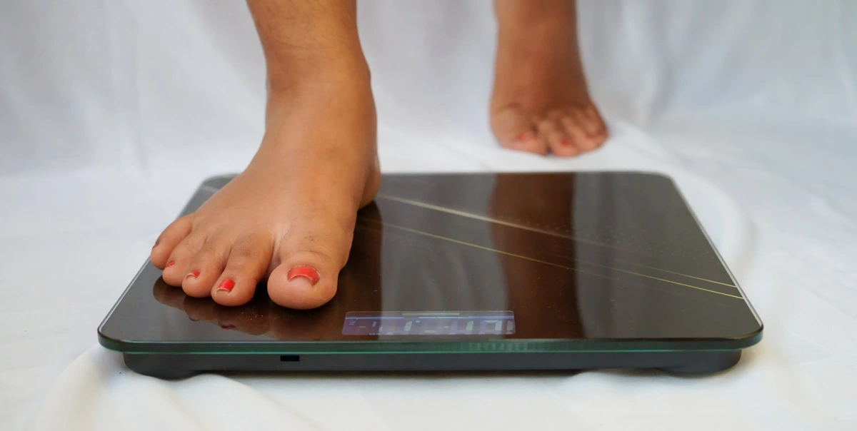Women stepping on weight scale to measure her weight after weight loss treatment at Nova Vita Wellness Centers in Cedar Park and Austin, TX